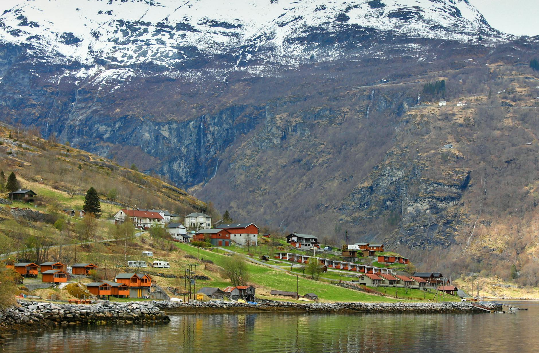 Norweska wioska w fiordzie otoczona ośnieżonymi górami nad spokojną wodą