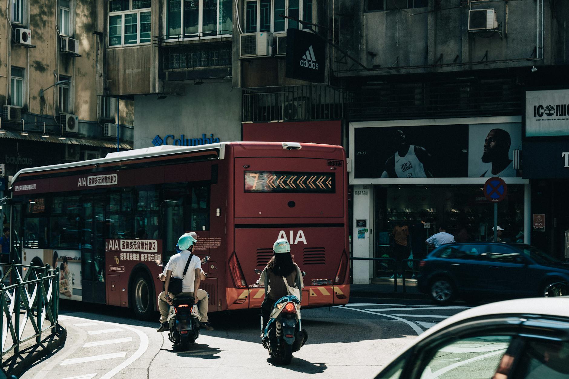Skuterzy za autobusem na ruchliwej ulicy w centrum Makau