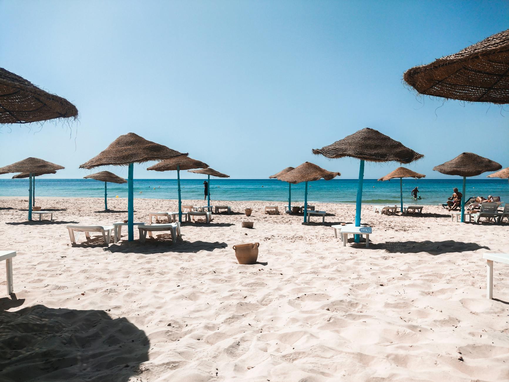 Spokojna piaszczysta plaża na Dżerbie z parasolami i turkusowym morzem
